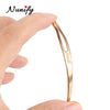 A hand holds a gold-toned stainless steel interlocking needle for loc maintenance.
