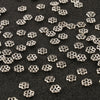 Small silver hollow flower bead caps scattered on a black surface for jewelry making