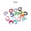 A collection of mixed colored metal open jump rings in various shades including red, purple, silver, green, and gold.