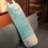 A light blue and white long body stuffed animal plush pillow with colorful heart-shaped accents resting on a gray sofa.