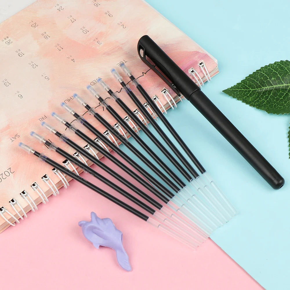 A set of black automatic fade pens with clear refills is displayed on pink and blue paper.