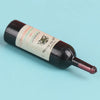 A dark glass miniature wine bottle with a pink liquid and a label for dollhouse decor.