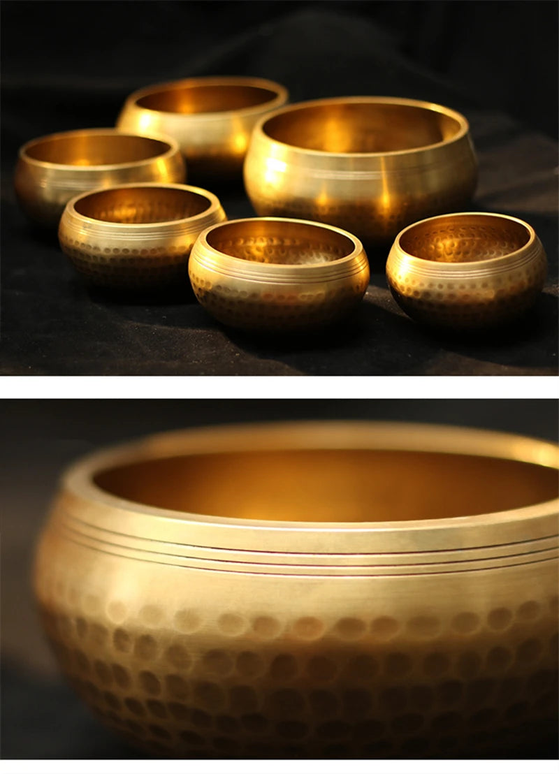 Several handmade copper singing bowls of varying sizes are displayed on a dark surface.