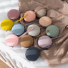 A collection of soft silicone pacifier holders in various pastel colors resting on a beige knitted fabric.