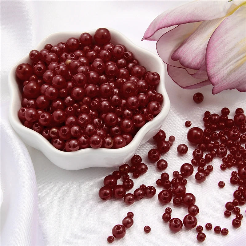 A pile of small, reddish-brown pearl beads scattered on a white surface.