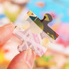 A hand holds a wooden jigsaw puzzle piece shaped like an animal, featuring various colors and patterns.