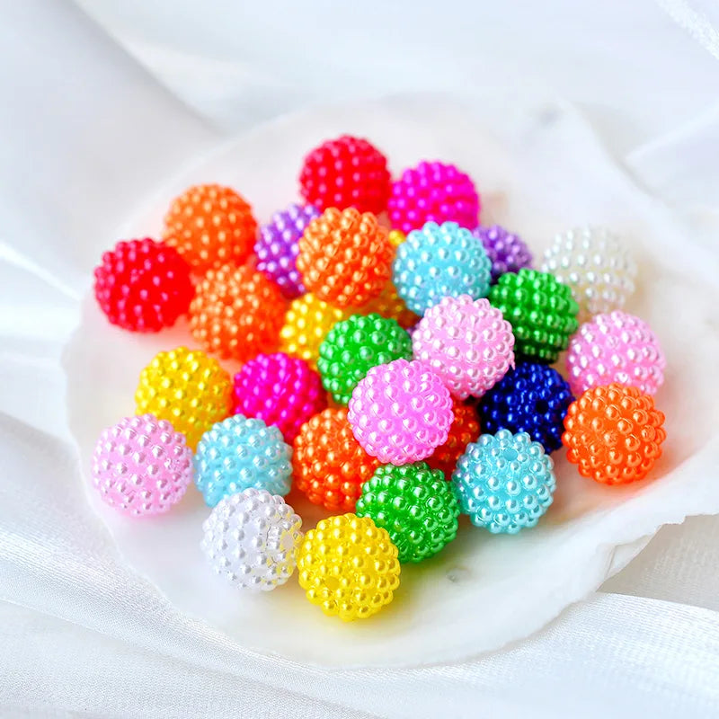 A collection of brightly colored acrylic pearl beads in various shades including red, orange, purple, pink, green, and blue s