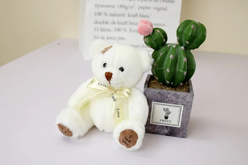 A white patch bear plush toy with a yellow bow and a small green cactus plant in a gray pot.