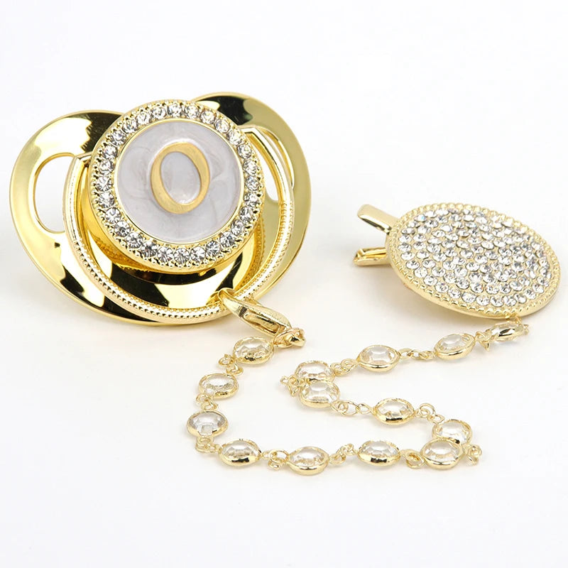 Gold and clear rhinestone pacifier featuring a personalized initial design on a clip.