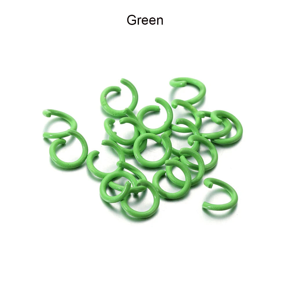A pile of green metal open jump rings for DIY jewelry making.