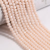 A close-up of light pink faceted crystal glass beads strung together in a long strand.