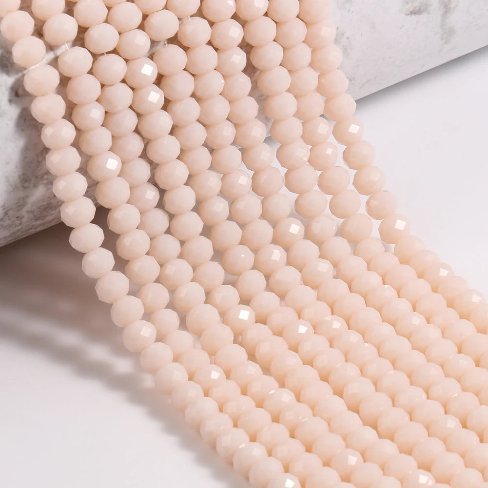 A close-up of light pink faceted crystal glass beads strung together in a long strand.