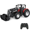 A black remote control tractor model with a trailer and lights is shown next to its controller.