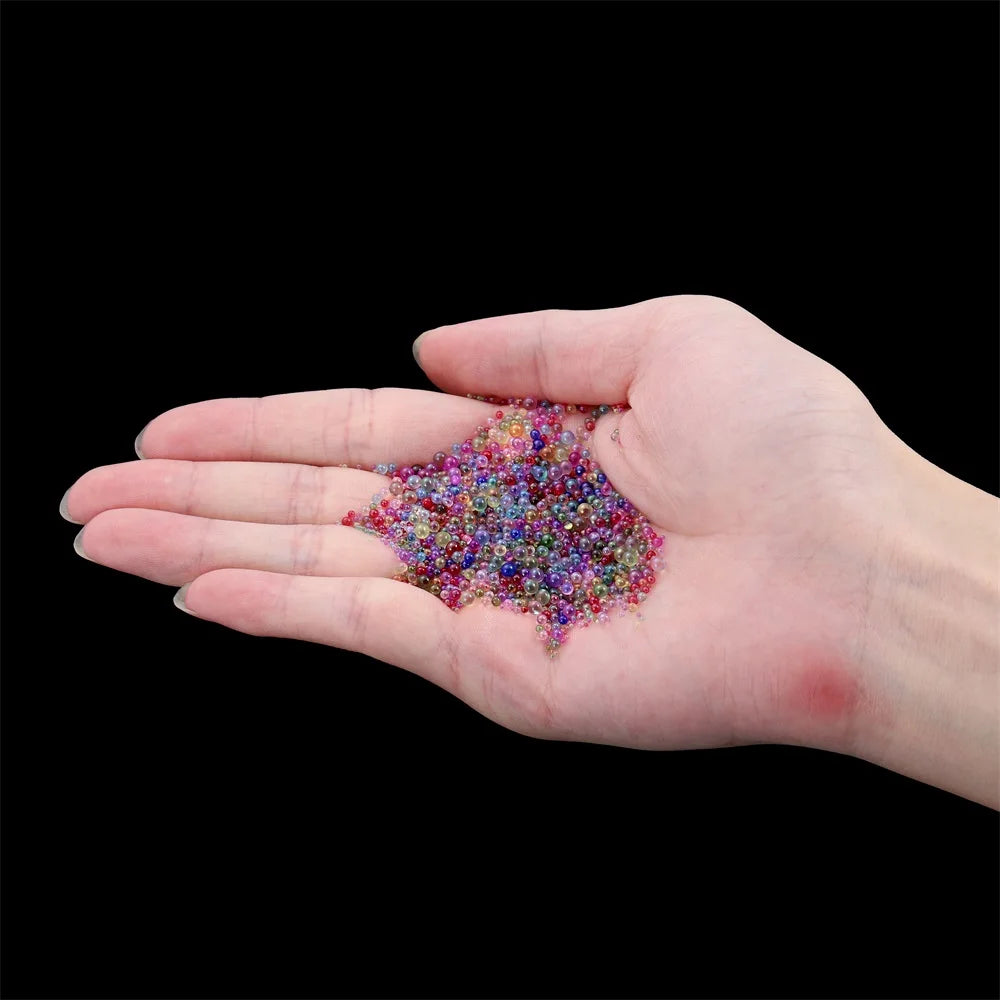 A hand holds a pile of multi-colored mini glass bubble beads for crafting.