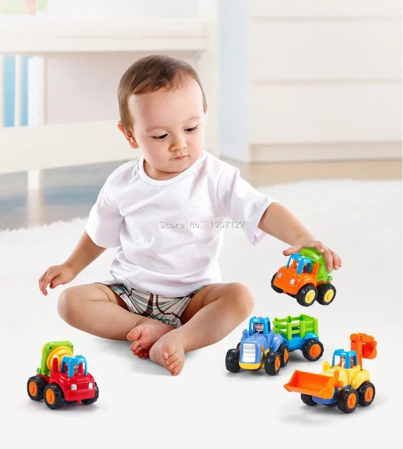 A baby is sitting on the floor surrounded by a 4-piece Kawaii mini construction vehicle toy set in various colors.