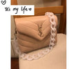 A light pink acrylic bag featuring a gold logo and adorned with a clear beaded chain strap.