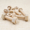 Wooden screw and nut building blocks made of light wood stacked on a beige fabric surface.