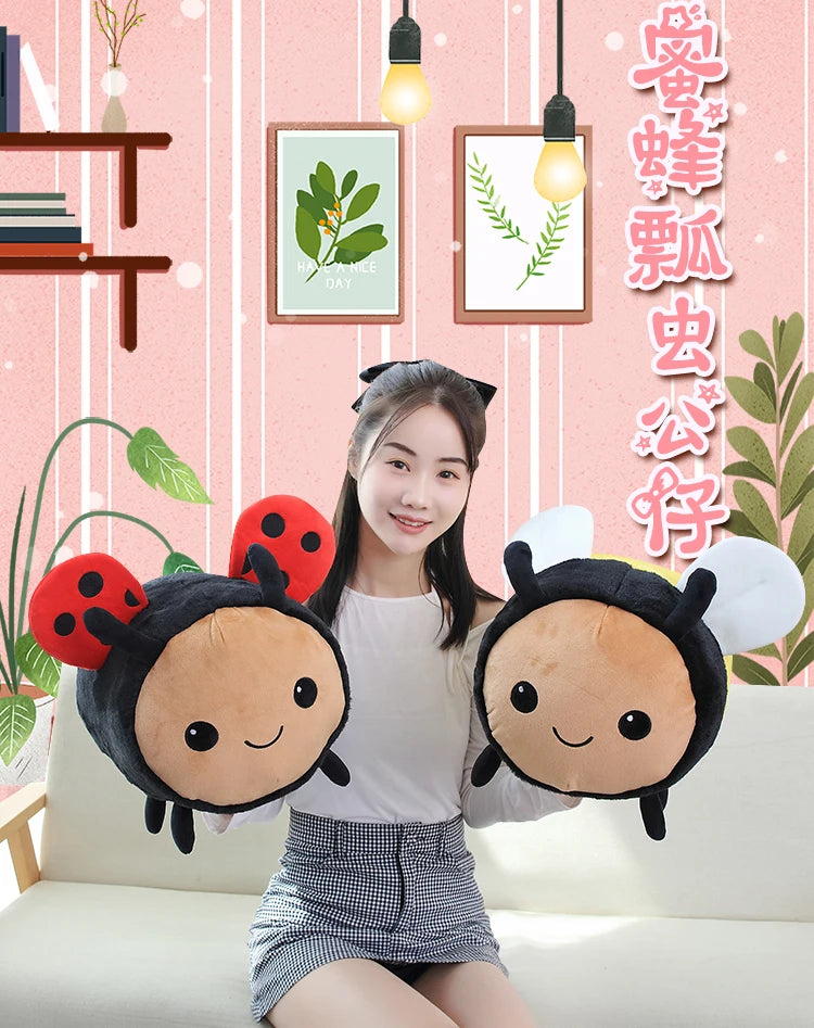 A young woman is holding two plush toys shaped like black and yellow ladybugs or bees against a pink striped background.