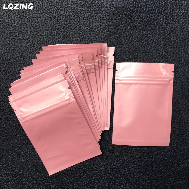 A stack of pink mini reusable ziplock bags with secure zippers is displayed on a dark surface.