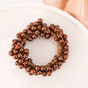 A wreath of dark brown, textured beads used as elegant pearl hair ties or bow scrunchies.