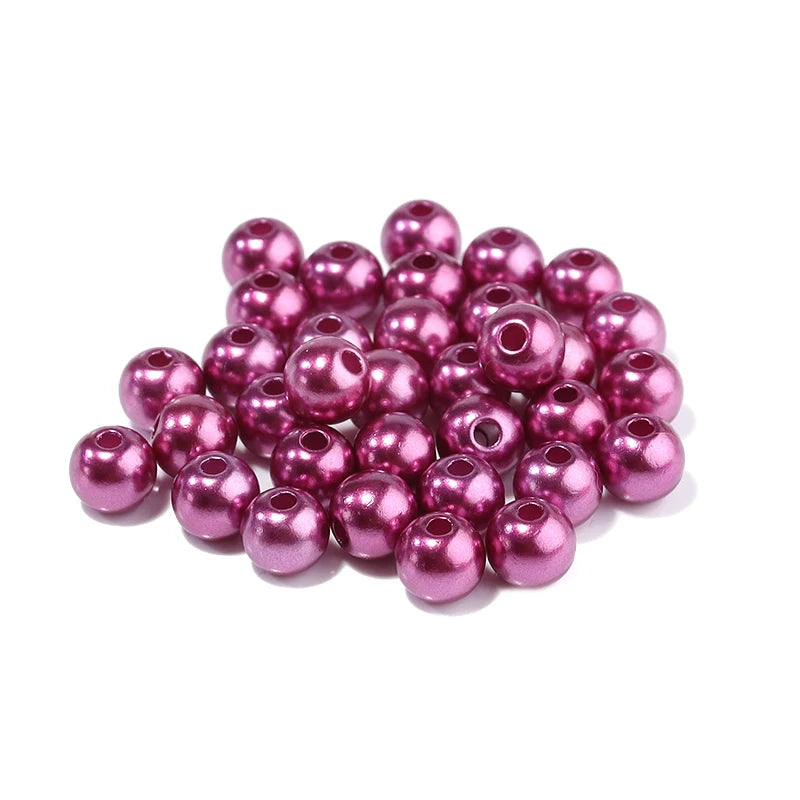 A pile of small, round, magenta imitation pearl beads for DIY jewelry making.
