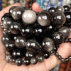 A hand holds a cluster of natural gemstone beads including tiger eye, lava, and turquoise for jewelry making.