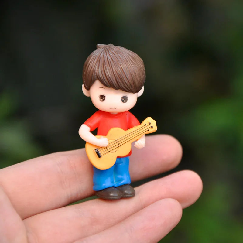 A small figurine of a boy playing a yellow guitar, held in a person's hand.