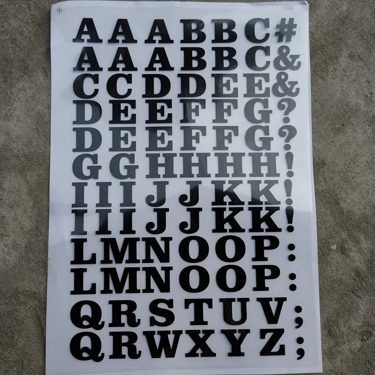 A sheet of DIY iron-on heat transfer patches showing various uppercase and lowercase letters and symbols.