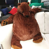 An oversized lifelike brown bear plush cushion sitting on a white sofa.