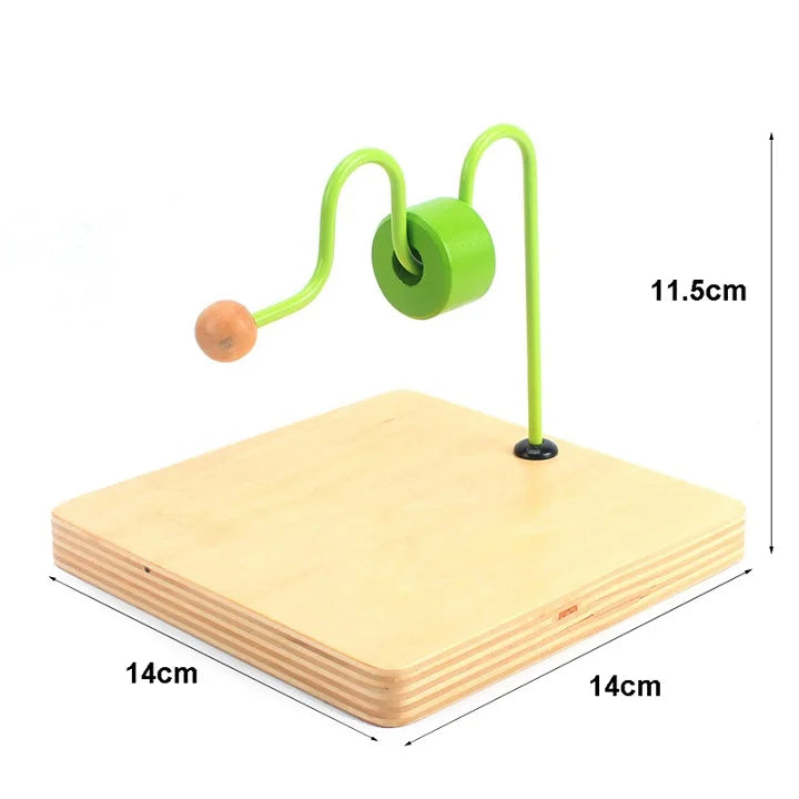 A green wooden sensory toy set with a handle and ball resting on a light wood board.