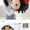 A young woman holds a black and orange bee ladybug plush toy against her white shirt and plaid skirt.