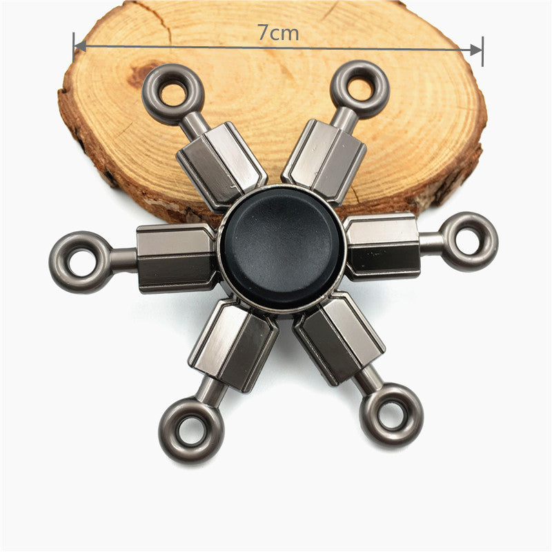 A metal fidget spinner with a rainbow finish is shown resting on a wooden surface.