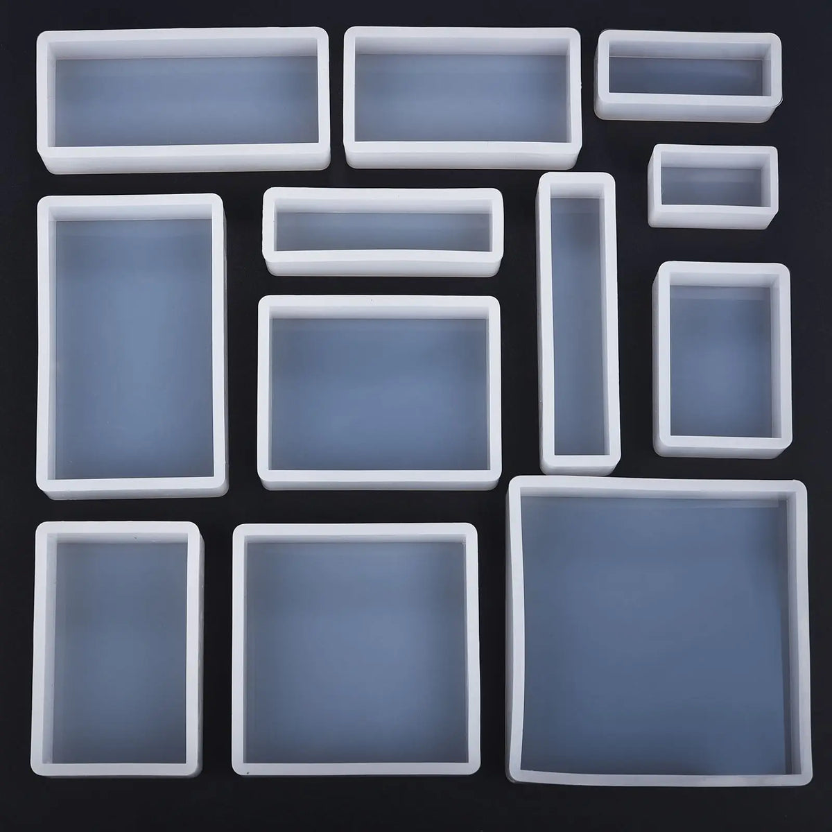 A collection of various geometric resin casting molds in translucent gray and white.