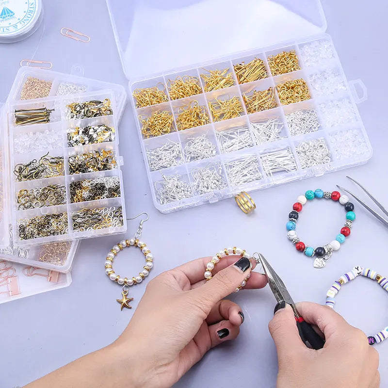 A hand is assembling jewelry using a complete kit of findings, tools, and beads in an open plastic box.