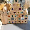A stack of wooden gemstone building blocks featuring various colored acrylic crystals.