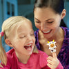 A smiling woman is looking down at a young girl who is holding an animal finger puppet.