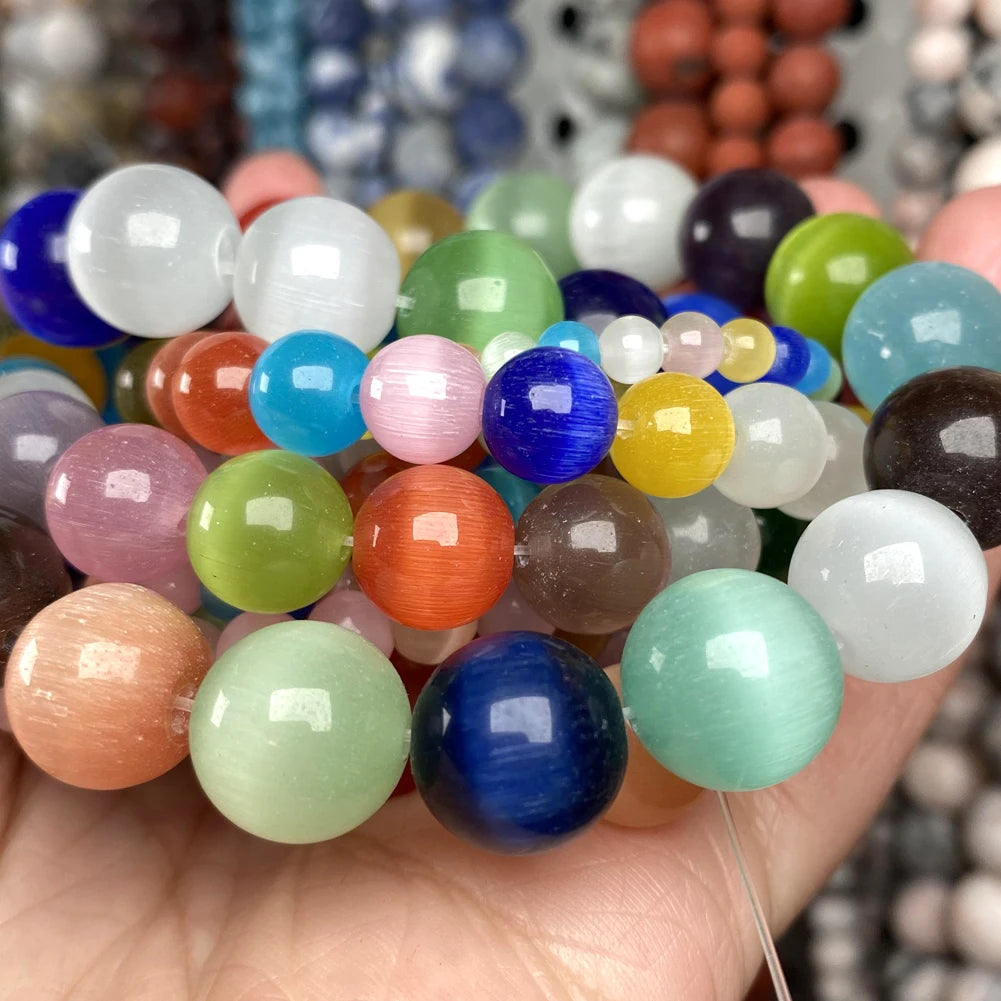 A collection of natural gemstone beads in various colors including blue, green, pink, and orange, held in a hand.