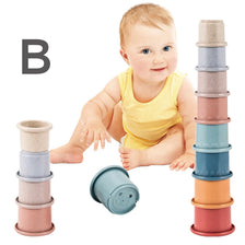 A baby is shown next to a set of stacked, boat-shaped plastic cups in various pastel colors.