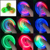 A collection of glow-in-the-dark LED fidget spinners demonstrating various colors and light effects.