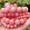 A pile of pink natural gemstone beads for jewelry making including tiger eye, lava, and turquoise stones
