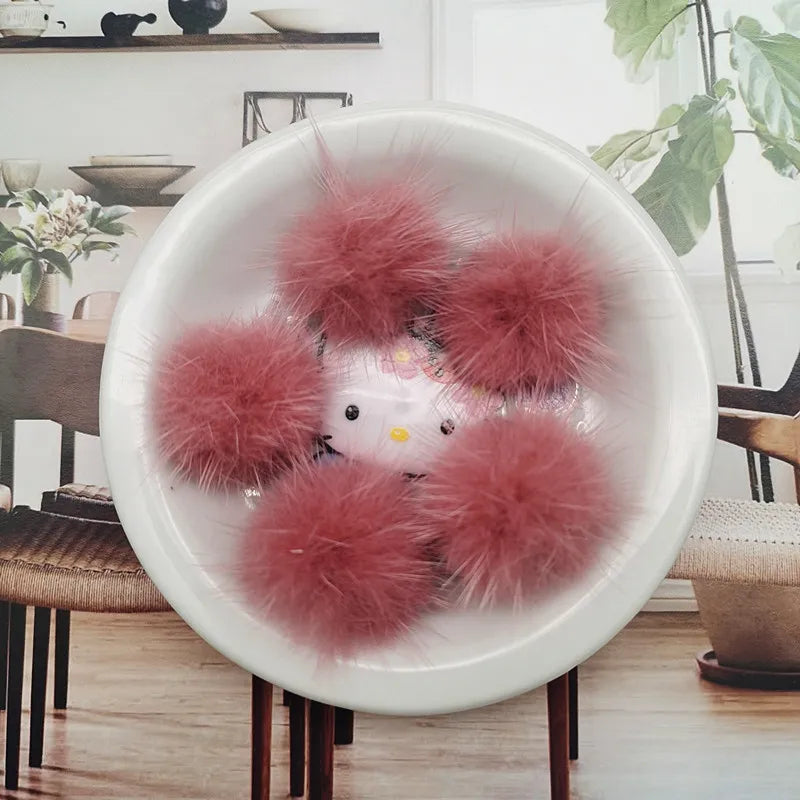 A white bowl filled with pink fluffy mink fur pom poms for crafts and accessories
