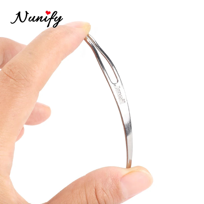 A hand holds a stainless steel interlocking needle used for loc maintenance.
