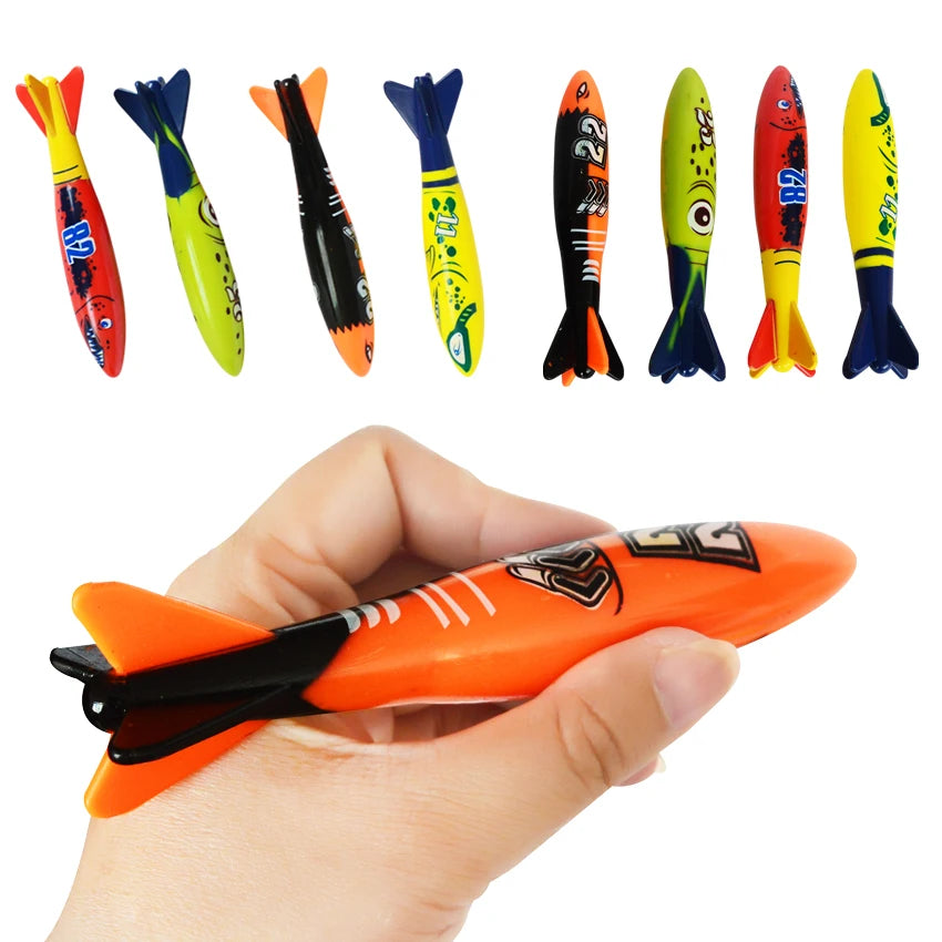 A hand holds an orange shark rocket pool diving toy alongside several colorful shark toys.