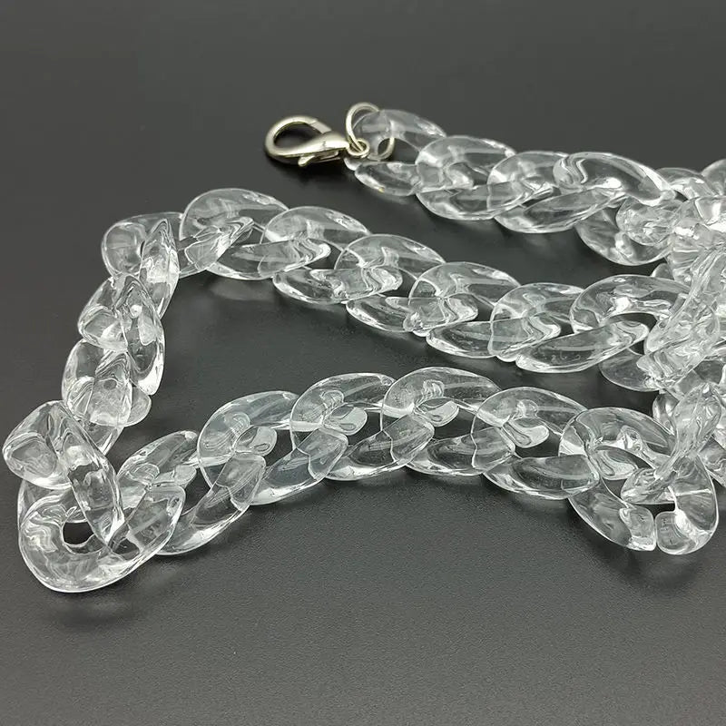 Clear acrylic bag chain strap with clips laid out on a dark surface.