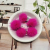A white bowl filled with bright pink fluffy mink fur pom poms for crafting.