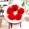 A pile of bright red mink fur pom poms displayed on a white plate.