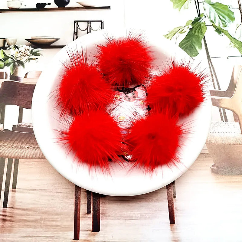 A pile of bright red mink fur pom poms displayed on a white plate.