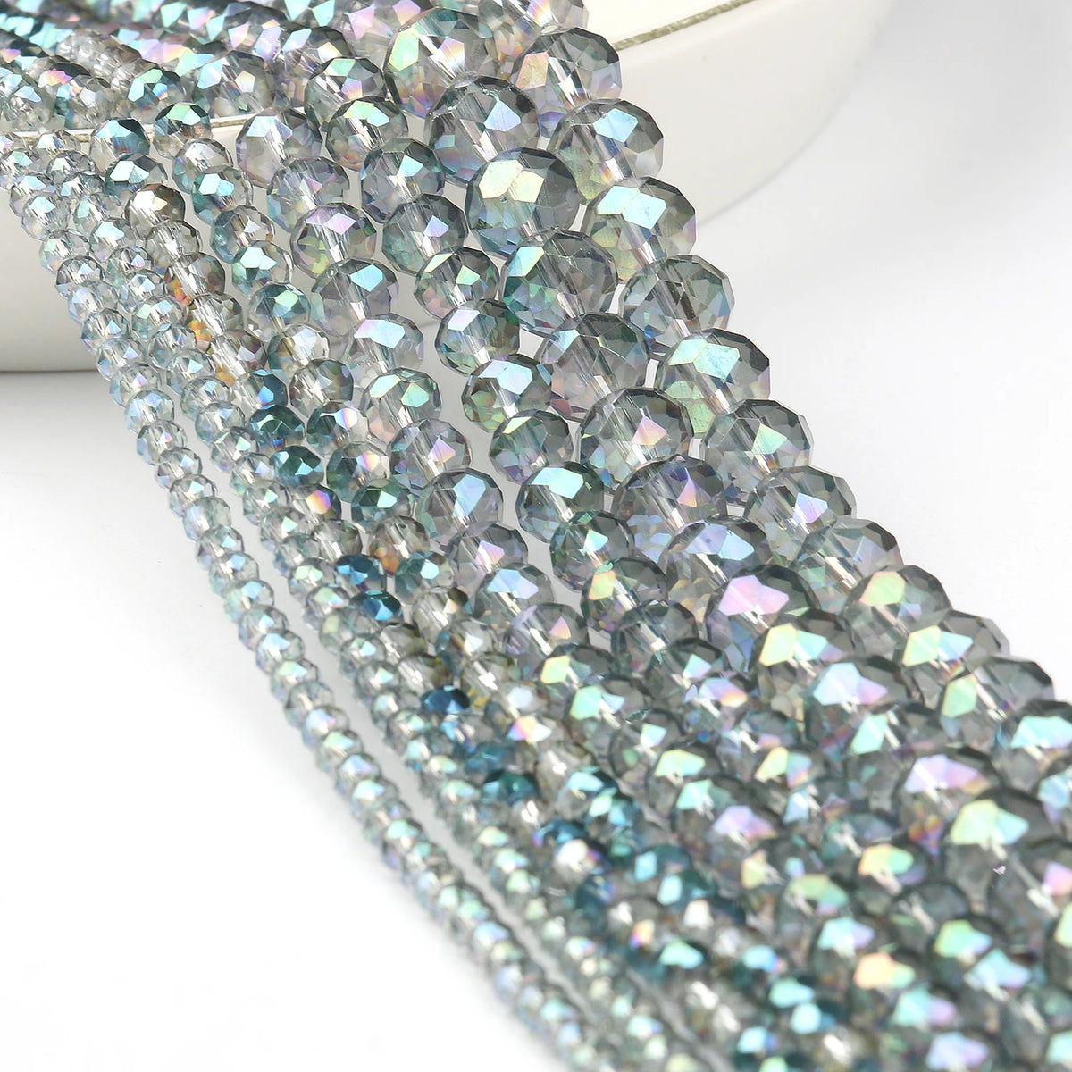 A close-up of a strand of iridescent, faceted crystal glass beads for jewelry making.