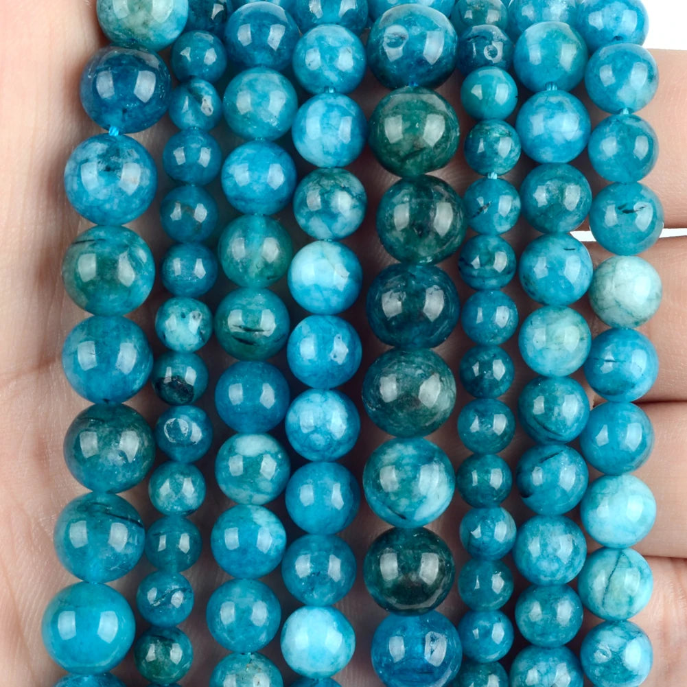 A collection of round gemstone beads in shades of blue and green, including turquoise and lava colors.