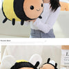 A plush toy of a bee and ladybug design with yellow and black coloring shown next to a woman.